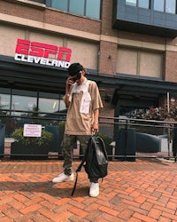 a man is standing on a brick sidewalk with a backpack